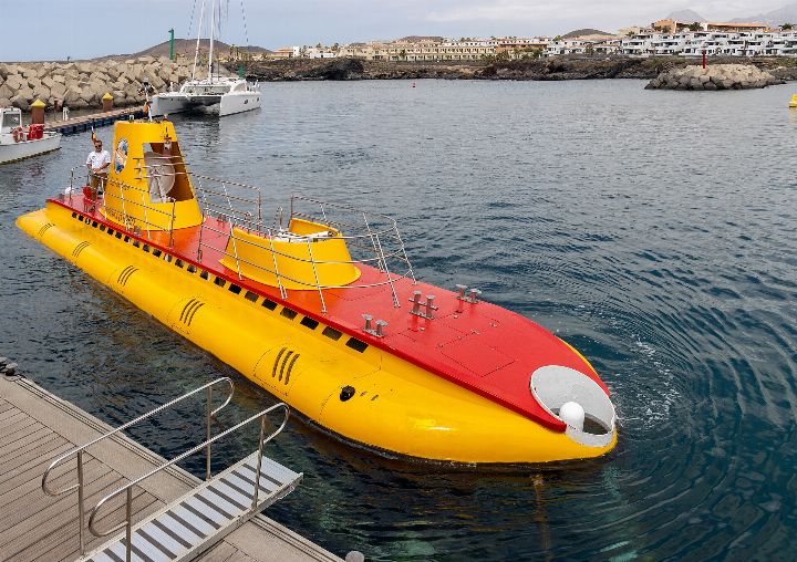 Yellow and red tourist submarine coming alongside a pontoon in a marina