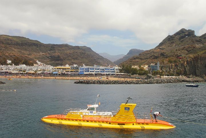 Yellow tourist submarine on the surface in front of the Mogán valley